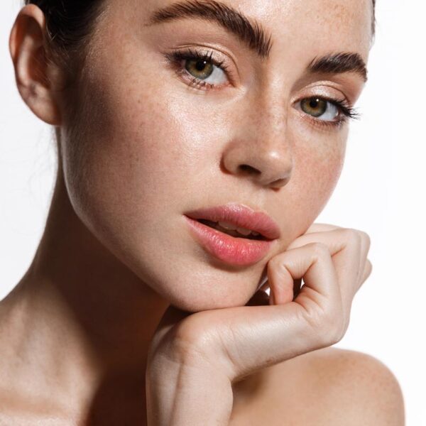 Attractive female model with natural makeup, glowing healthy skin after shower, looking sensual at camera, touching her face, showing moisturizer cream after-effect, white background Attractive female model with natural makeup, glowing healthy skin after shower, looking sensual at camera, touching her face, showing moisturizer cream after-effect, white background.